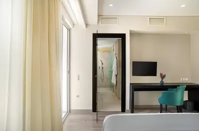 a bedroom with a bed and a desk and a television at Hotel Lozenge in Athens
