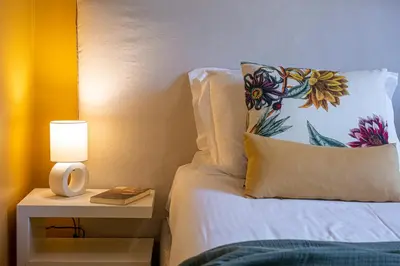 a bed with a pillow and a nightstand with a lamp at Hidesign Athens Plaka Apartment in Acropolis in Athens