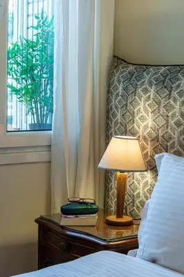 a bed with a lamp on a table next to a window at Hidesign Athens Plaka Apartment in Acropolis in Athens