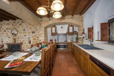 a large kitchen with wooden cabinets and a stone wall at Four Seasons Stonework Castle in Lagonissi