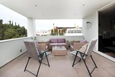 a patio with chairs and a couch on a balcony at Athens Lycabettus Hill Penthouse, Private Roof Garden & Pool in Athens