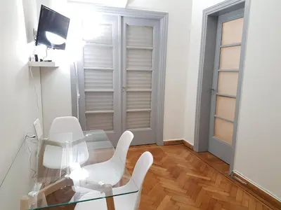 a white dining room with a glass table and white chairs at Errathens Pine Red and Taupe - Athens Center in Athens