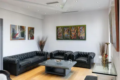 a living room with black leather couches and a table at Acropolis Elegant Penthouse in Athens