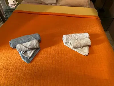 two towels on a bed with an orange sheet at Soho Athene Apartment in Athens