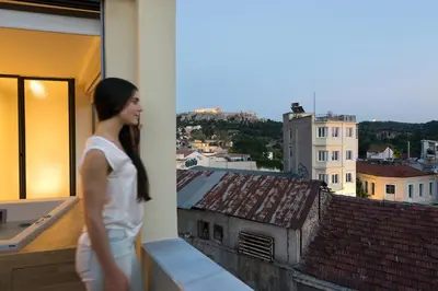 a woman standing on a balcony looking out of a window at Acropolis View Luxury Apartment in Athens