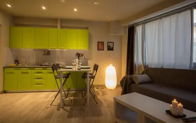 a living room with a couch and a kitchen with green cabinets at Athens Suites in Athens