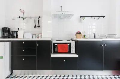 a kitchen with black and white cabinets and a microwave at Karitsi Place in Athens