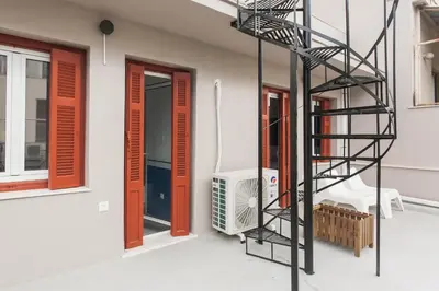 a spiral staircase next to a building with red doors at Karitsi Place in Athens