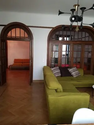 a living room with a green couch and a chandelier at Kolonaki Deco Apartment in Athens