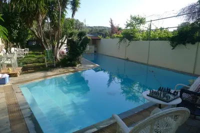 a large blue swimming pool with chairs next to a fence at St. Thomas Bed and Breakfast in Paianía