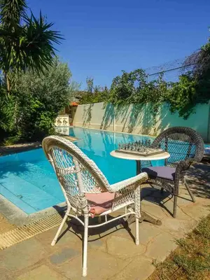 two wicker chairs and a table next to a pool at St. Thomas Bed and Breakfast in Paianía