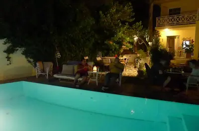 a group of people sitting around a pool at night at St. Thomas Bed and Breakfast in Paianía