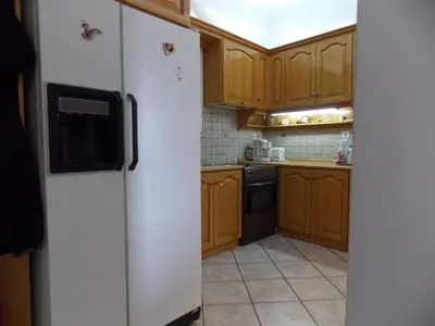 a kitchen with wooden cabinets and a white refrigerator at Pasalimani Long Beach in Piraeus