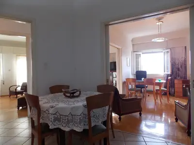 a dining room and living room with a table and chairs at Pasalimani Long Beach in Piraeus
