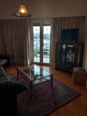 a living room with a glass coffee table and a television at Pasalimani Long Beach in Piraeus