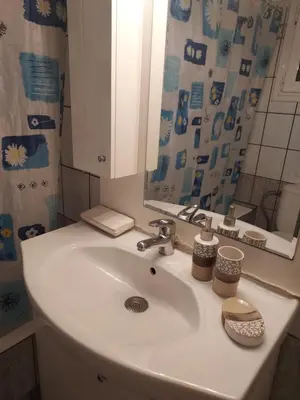 a bathroom sink with a mirror and a shower curtain at Pasalimani Long Beach in Piraeus