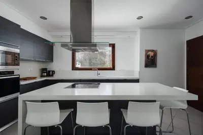 a kitchen with a large white island with white stools at Villa Saronida in Saronida