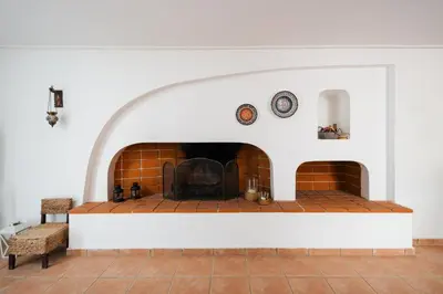 a living room with a brick fireplace with two clocks at Villa Saronida in Saronida