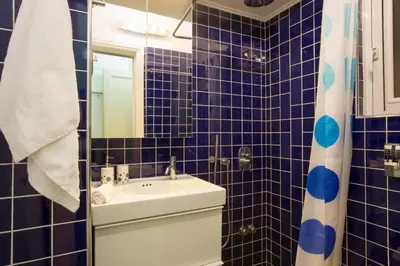 a blue tiled bathroom with a toilet and a sink at Apartment at Acropolis Museum by YHA in Athens