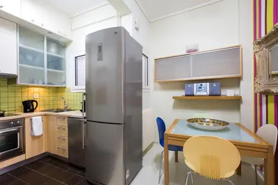 a kitchen with a stainless steel refrigerator and a table at Apartment at Acropolis Museum by YHA in Athens