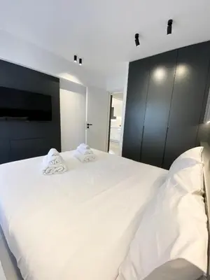 a bedroom with a large white bed and black cabinets at Seafront Apartment by C2C Architects in Kalívia Thorikoú