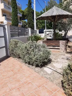a patio with a bench and an umbrella and bushes at Villa Alexandra in Agia Marina Aegina