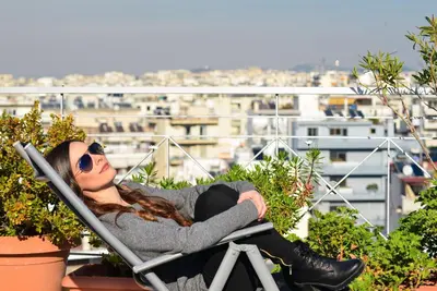 a woman sitting in a chair on a balcony at Kalypso Apartment in Athens