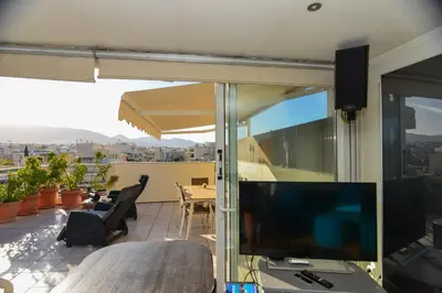 a balcony with a television and a table and chairs at Kalypso Apartment in Athens