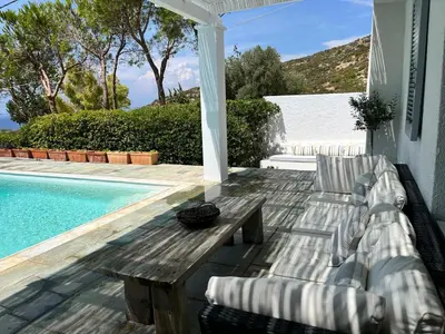 a patio with a table and chairs next to a pool at Saronida Boutique Villa Private Pool, Sea views, Lovely Gardens & Roof Terrace in Saronida