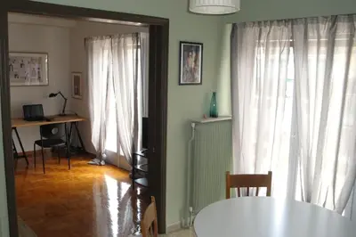 a dining room with white curtains and a table at Illisia Roof Apartment in Athens
