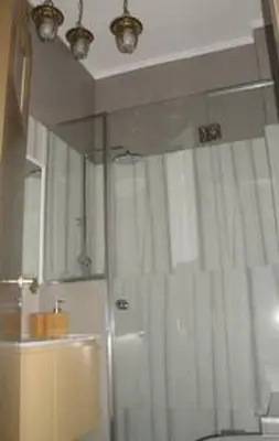 a bathroom with a shower with a white shower curtain at Illisia Roof Apartment in Athens