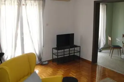 a living room with a yellow couch and a television at Illisia Roof Apartment in Athens
