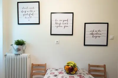 a table with a bowl of fruit and three pictures on the wall at Blue Ark Athenian Nest in Athens