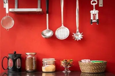 a kitchen counter with utensils hanging on a red wall at Comfort Stay Lofts in Athens