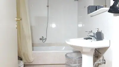 a white bathroom with a sink and a shower at Errathens Wheat Apartment - Athens Center, 3 BD, 1 BATH in Athens