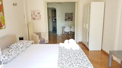 a bedroom with a white bed and a living room at Errathens Wheat Apartment - Athens Center, 3 BD, 1 BATH in Athens