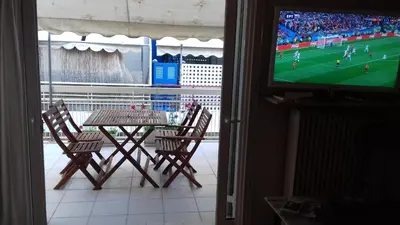 a table and chairs and a television with a soccer game at Flat31 in Athens