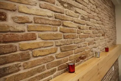 a brick wall with two red cups on a wooden shelf at George Studio in Athens
