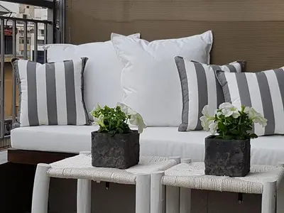 a couch with striped pillows and two tables with plants at ADMETUS PSYRRI LOFT by K&K in Athens