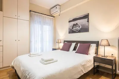 a bedroom with a large white bed and a window at Stylish Athens Apt 10 Minute Walk to Acropolis Museum & Metro in Athens