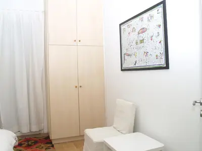 a bedroom with a white chair and a cabinet at Artistic Deco Apartment in Athens