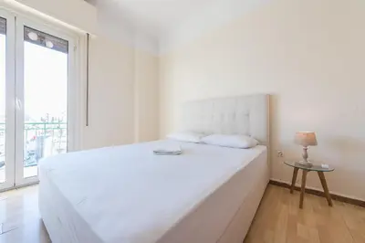 a white bed in a white bedroom with a window at Super Paradise Apartments in Athens