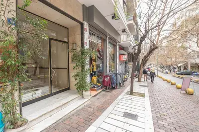 a store on a street with people walking in front of it at Victoria Sun Apartments in Athens