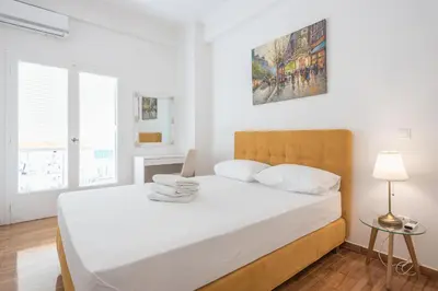 a white bedroom with a large bed with white sheets at Victoria Sun Apartments in Athens