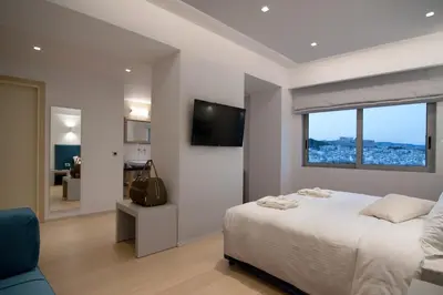 a white bedroom with a bed and a window at Athenaeum Grand Hotel in Athens