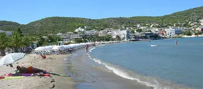 a beach with umbrellas and people laying on the sand at Παραθαλασσια στουντιο Μιχαλιας Sea view studio Michalias in Agia Marina Aegina