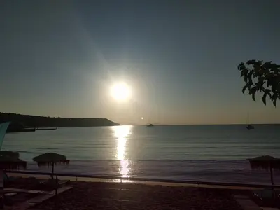 a sun setting over the water with a beach at Παραθαλασσια στουντιο Μιχαλιας Sea view studio Michalias in Agia Marina Aegina