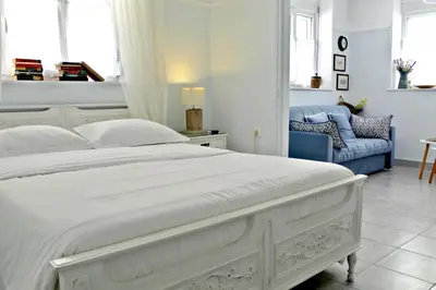 a bedroom with a white bed and a blue couch at By the Acropolis, In the heart of Plaka! in Athens