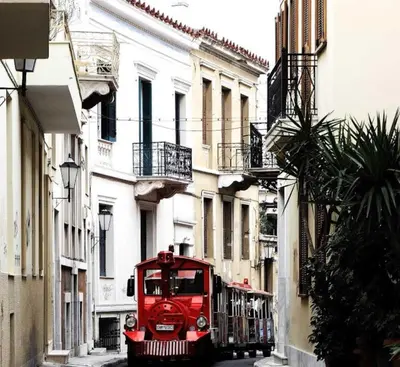 a red truck driving down a city street at By the Acropolis, In the heart of Plaka! in Athens