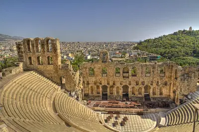 an ancient amphitheater with a city in the background at Back to Tradition, by the Acropolis! in Athens